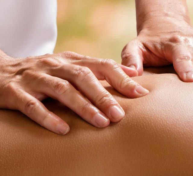 Hände eines Masseurs auf Frauenrücken