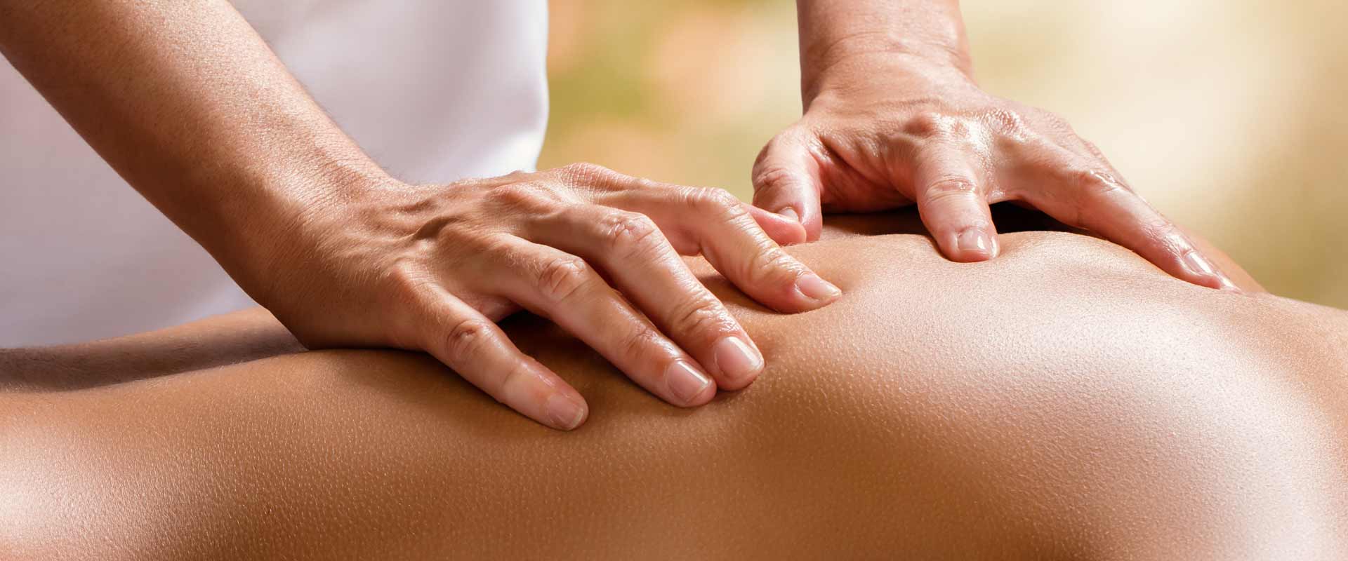 Hände eines Masseurs auf Frauenrücken